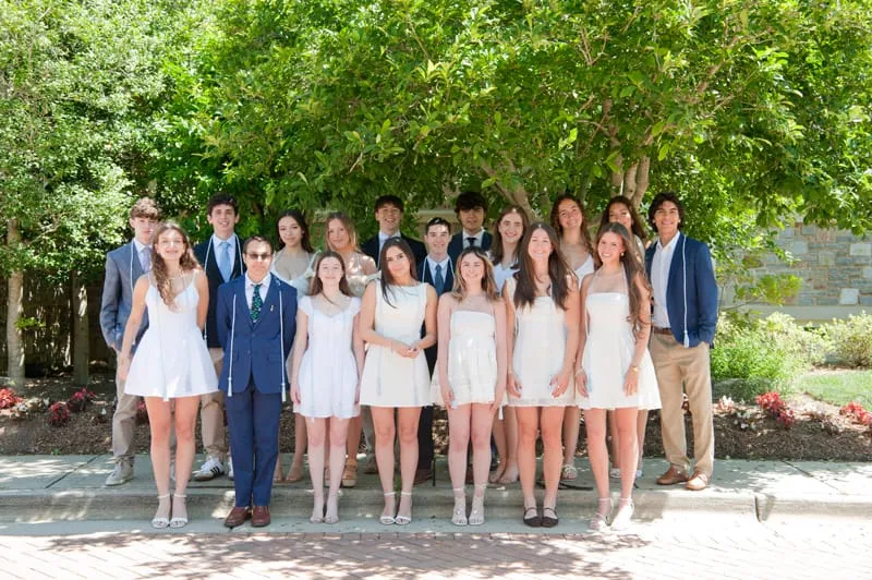 Egresados de la promoción 2026, vestidos de fiesta, en el jardín de la Escuela.