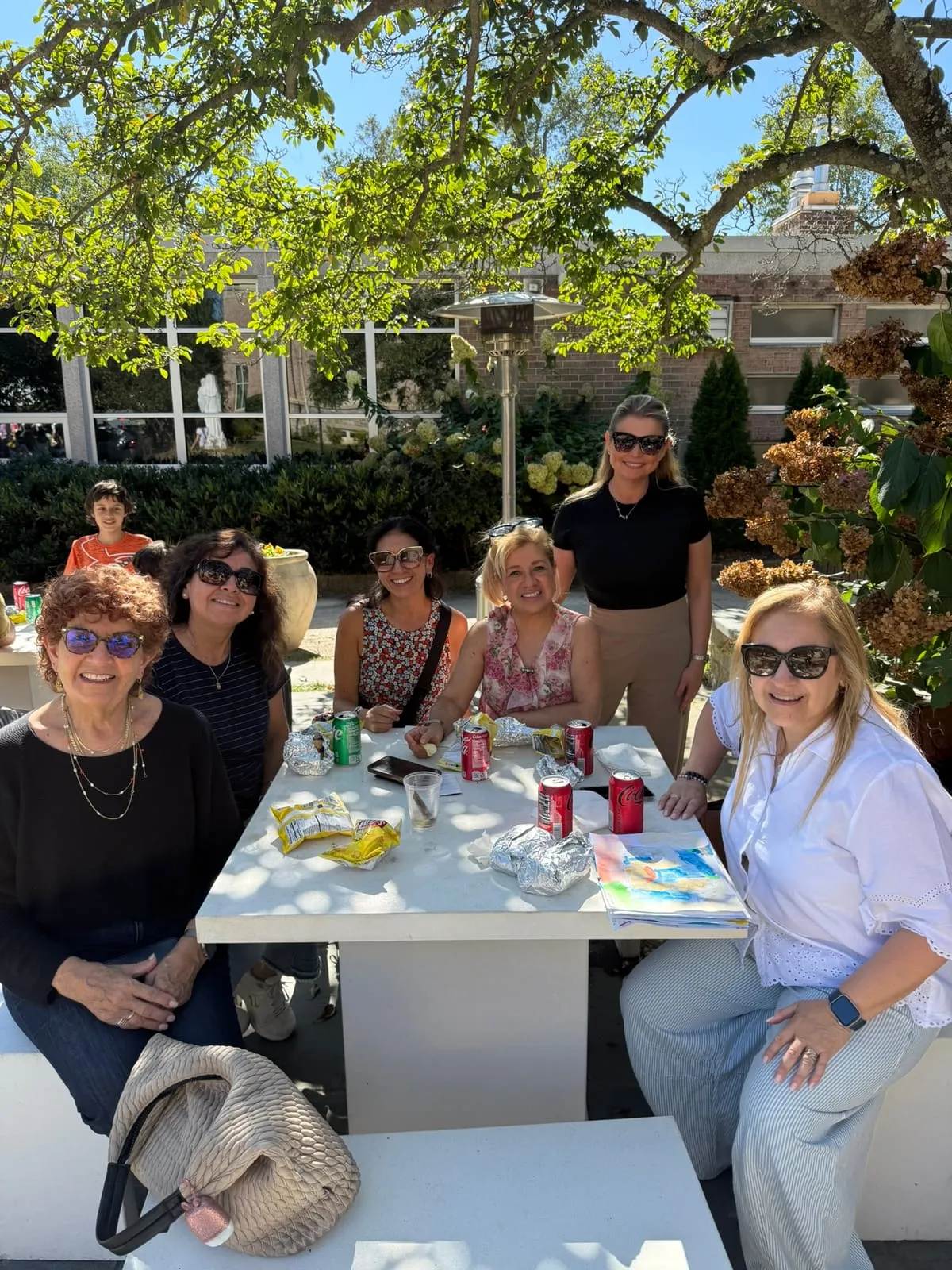 Familias de la Escuela compartiendo una mesa al aire libre en el picnic del 25 de Mayo.