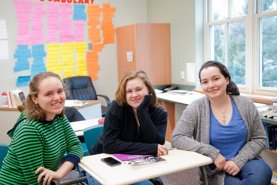 Tres estudiantes secundarios conversando en un aula durante un curso de AP.