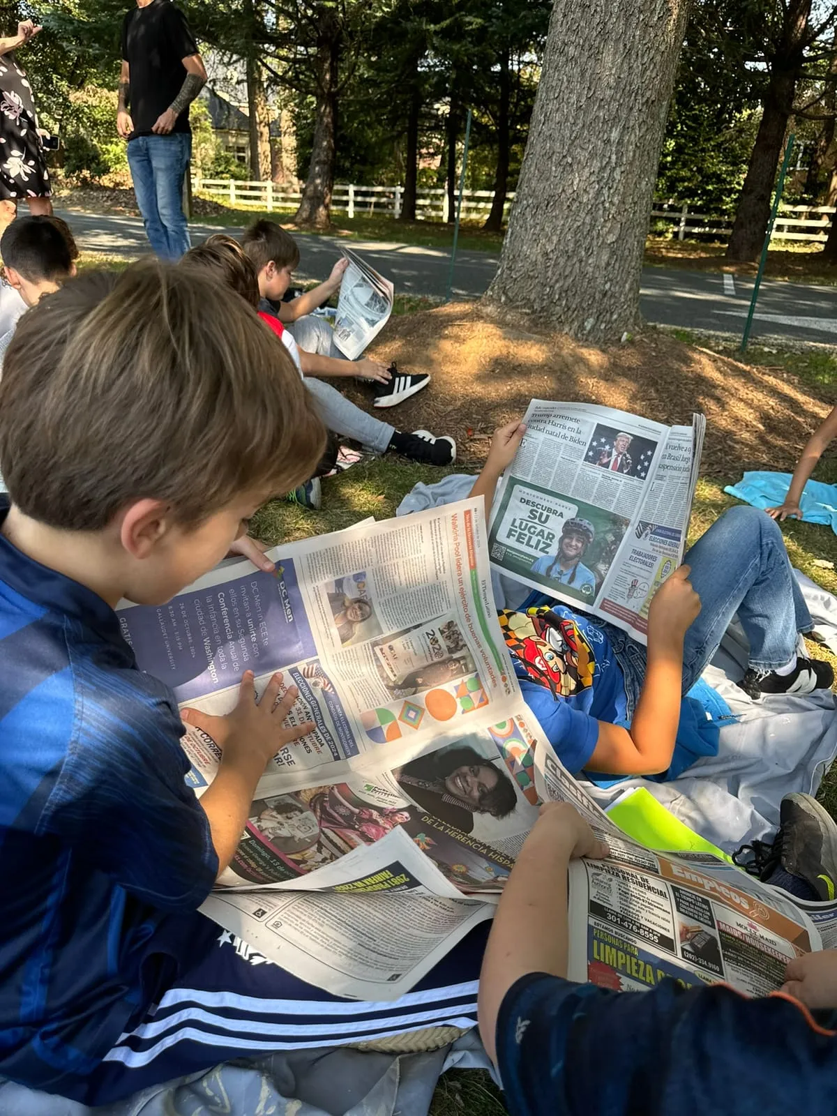 Un alumno lee al aire libre, recostado en el pasto, durante la maratón de lectura.