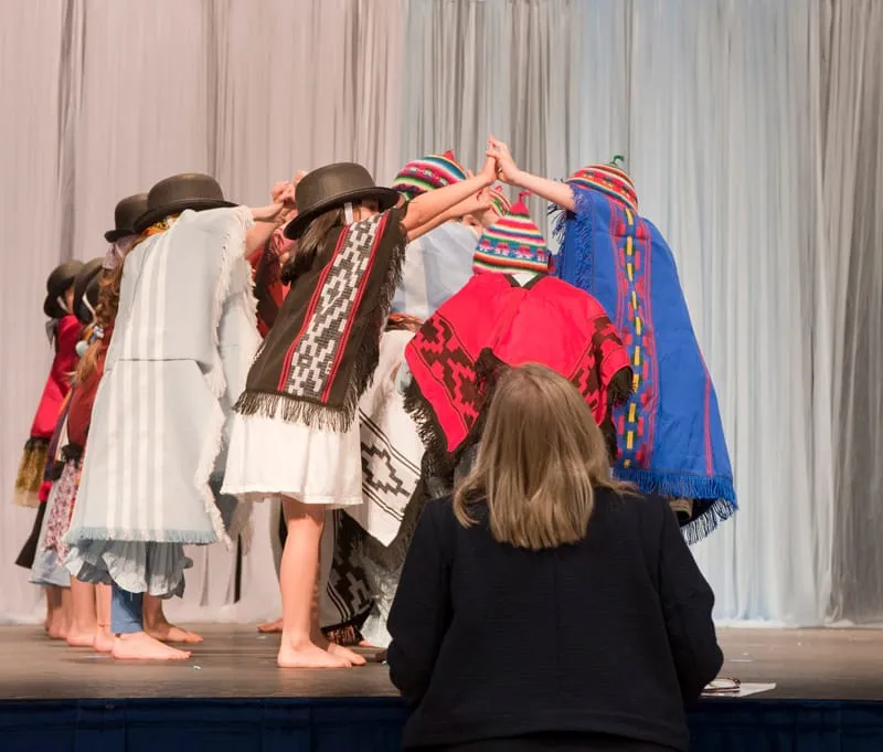 Alumnos con trajes típicos en el escenario durante el acto del 25 de Mayo.